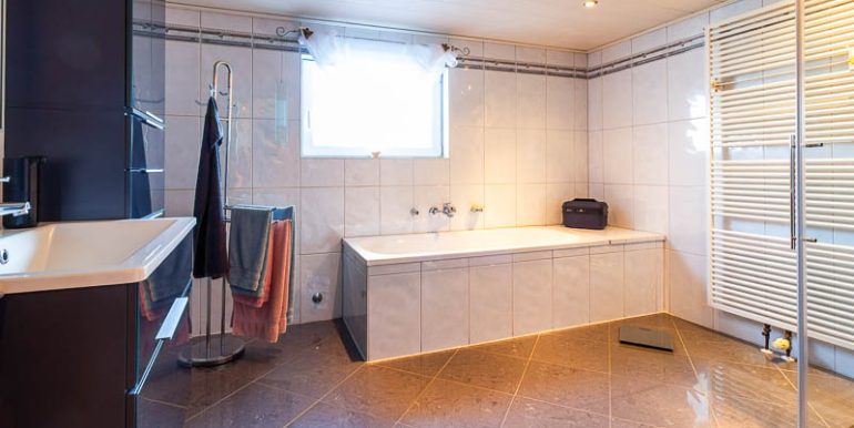 Geräumiges Badezimmer mit eleganter Badewanne, Handtuchständer und großem Fenster.