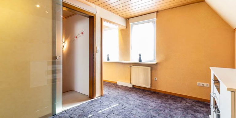 Helles Kinderzimmer mit Teppichboden, zwei Fenstern und modernem Glasschiebetür-Zugang.