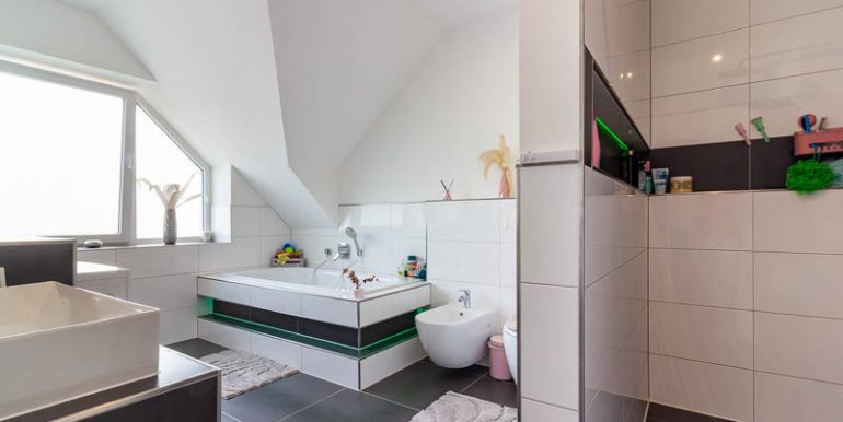 Elegantes Badezimmer mit klaren Linien, großformatigen Fliesen und stimmiger Lichtgestaltung.