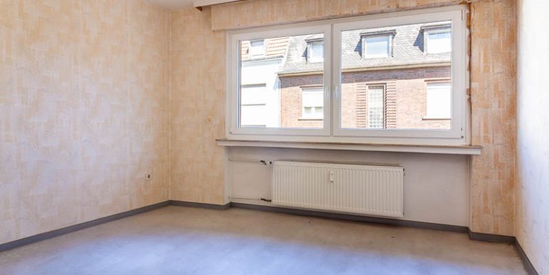 Helles Schlafzimmer mit großem Fenster – viel Potenzial für einen gemütlichen Rückzugsort.